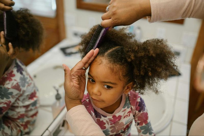 Mother Parting Daughter’s Hair with Brush