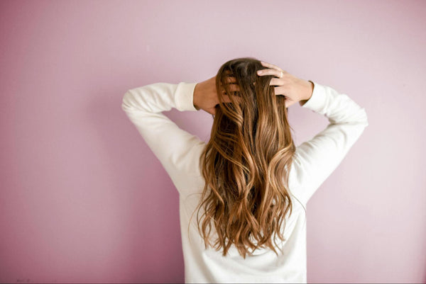 Woman touching her hair in front of pink backdrop