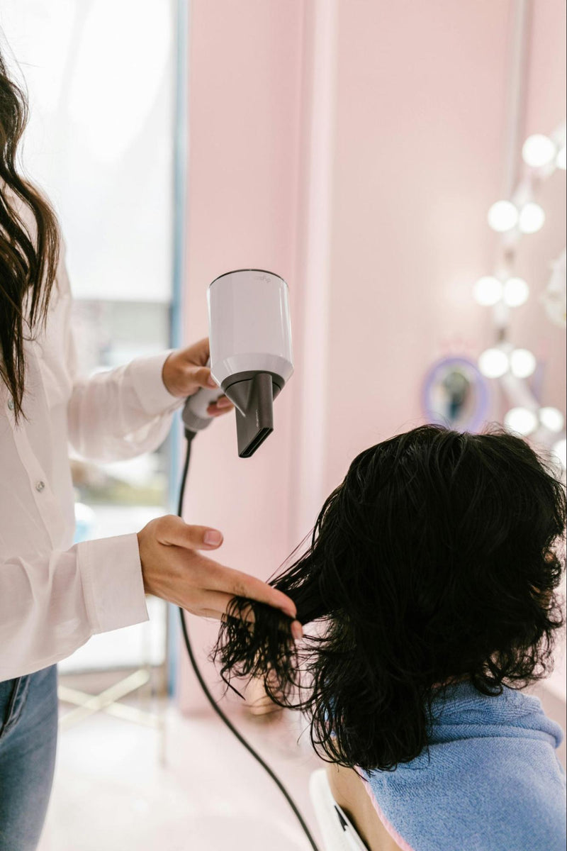 Woman Drying Another Woman’s Hair in Salon