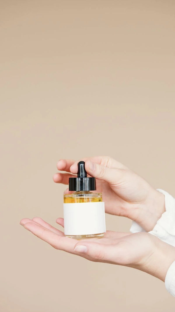 A person’s hands holding a small bottle of castor oil.