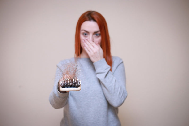 A woman holding a brush with hair.