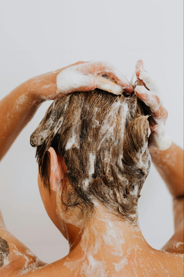 A person washing their hair with shampoo.