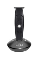 Black electric hair trimmer on a round charging base, with metal cutting comb.