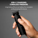 Matte black cordless hair trimmer in hand with power button