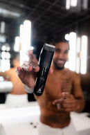 Black body trimmer held in hand with silver comb head and round power button
