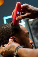 Red cordless hair clipper grooming facial hair with the display lit