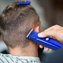 Blue electric hair trimmer in hand, cutting comb near the back of the head.
