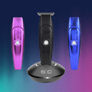 Three hair trimmers (pink, black, blue) with charging dock base