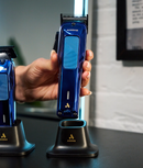 Andis Phenom navy clipper held above its charging stand