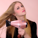 Rose gold ionic hair dryer with black concentrator nozzle held in hand
