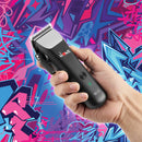 Black cordless hair clipper held in hand with green indicator light and guard