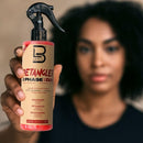 Hand holding hair detangling spray bottle with black sprayer and beige pink label.