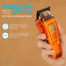 Orange cordless hair clipper held in hand with guard comb
