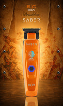 Orange cordless hair trimmer on base with black cutting blade and SABER panel