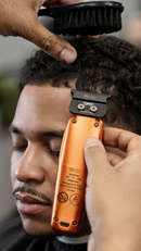Orange hair trimmer in use on face with black cutting comb on top