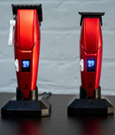 Red cordless hair clipper pair on charging bases with blue digital displays