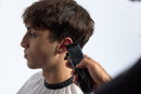 Black cordless hair clipper at side of head, blue-lit control panel