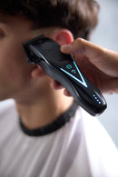 Wahl cordless hair clipper held to hair near the ear, with blue light indicators