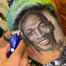 Blue electric hair trimmer being used on short hair; metal cutting head near scalp.