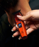 Andis cordless hair trimmer in hand, red and black with LED display