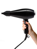 Black hair dryer held in hand with power cord