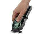 Cordless skin clipper in hand, green body with metal trimming head